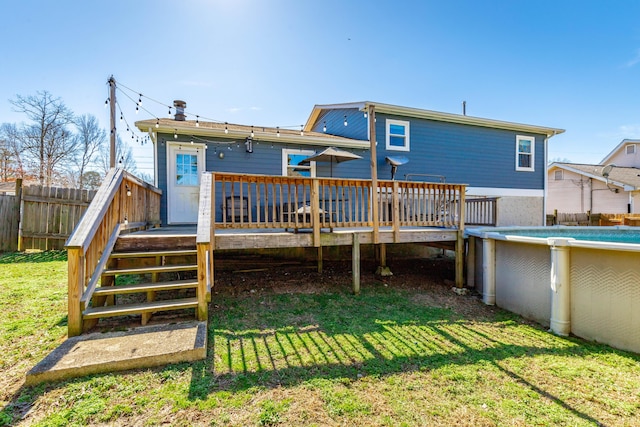 back of property featuring a yard, fence, a wooden deck, and a fenced in pool