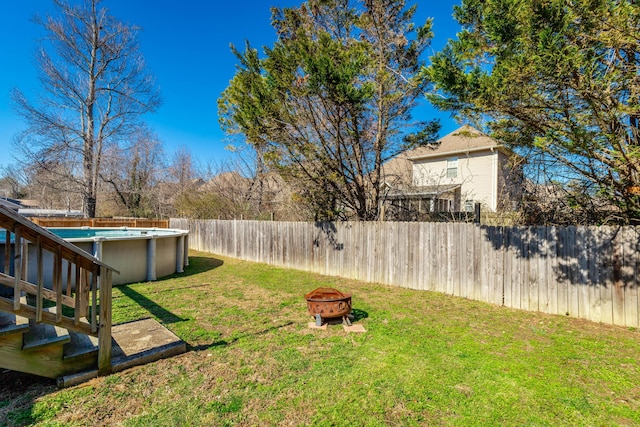 view of yard with a fenced in pool, a fenced backyard, and a fire pit