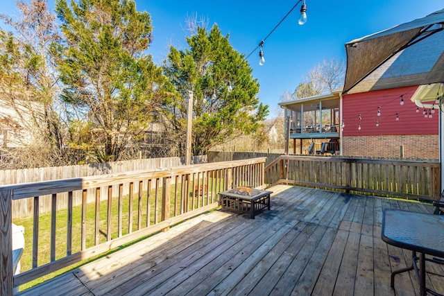 wooden terrace with a fenced backyard and a sunroom