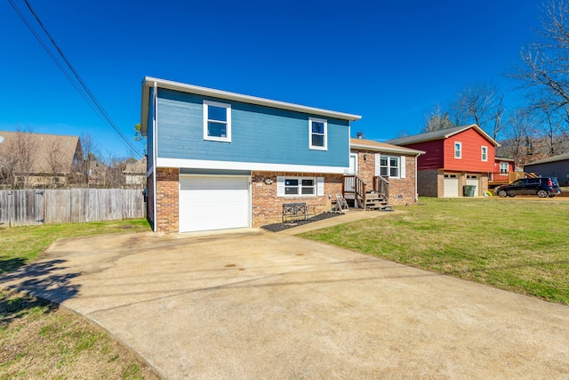 split level home featuring brick siding, concrete driveway, a front yard, fence, and a garage