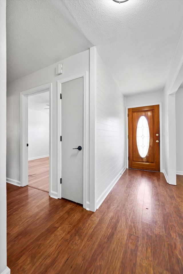 entryway with dark wood-style floors, a textured ceiling, and baseboards