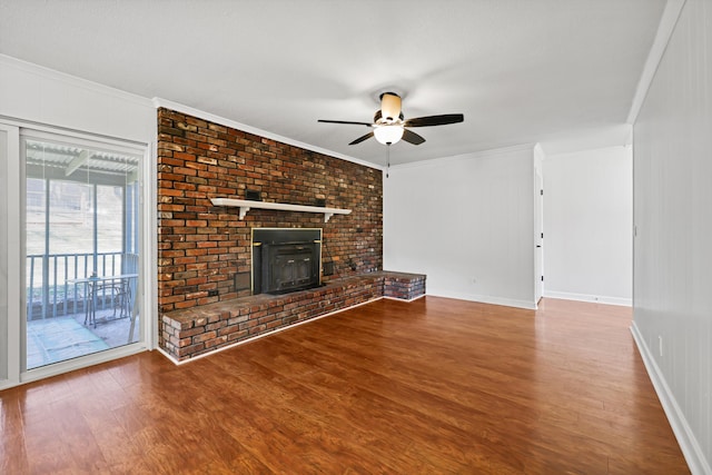 unfurnished living room with baseboards, ceiling fan, ornamental molding, wood finished floors, and a wood stove