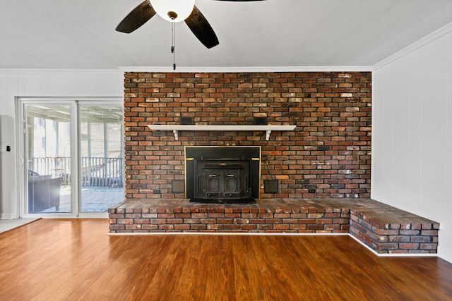 unfurnished living room with a wood stove, crown molding, a textured ceiling, and wood finished floors