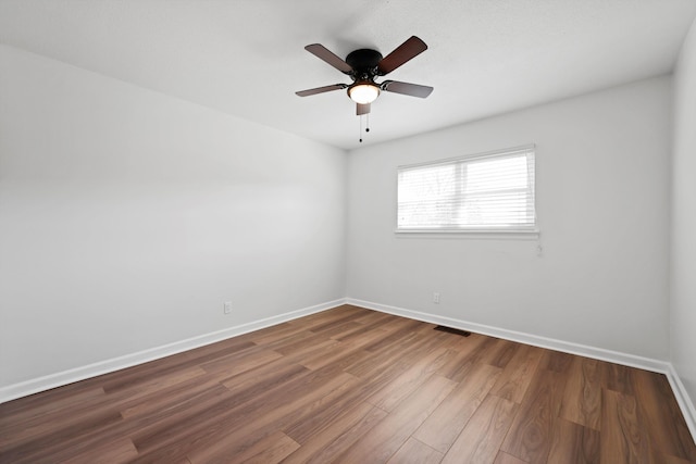 spare room featuring visible vents, ceiling fan, baseboards, and wood finished floors