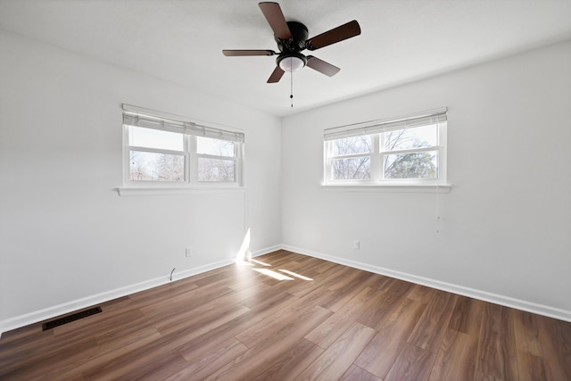 unfurnished room with baseboards, visible vents, ceiling fan, and wood finished floors