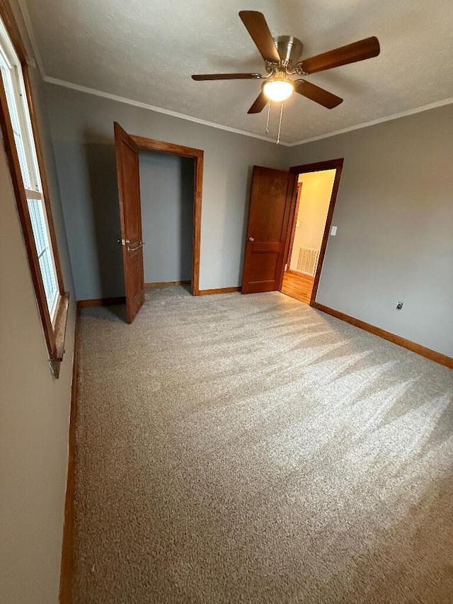 unfurnished bedroom with light carpet, crown molding, and a closet