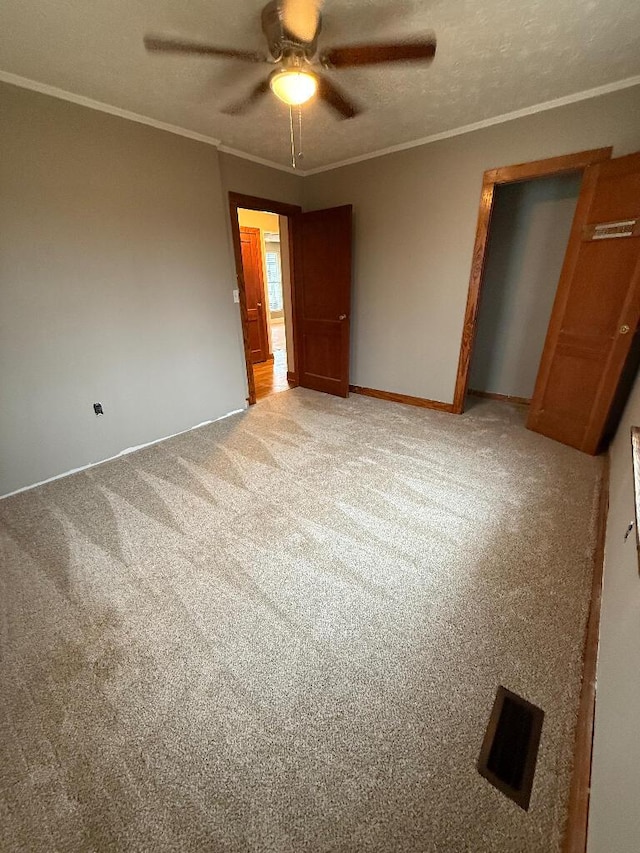 unfurnished bedroom with ornamental molding, carpet, ceiling fan, and a textured ceiling