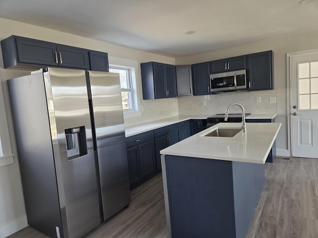 kitchen with appliances with stainless steel finishes, sink, dark hardwood / wood-style flooring, and an island with sink