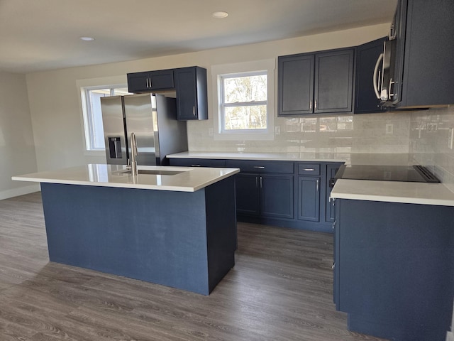 kitchen with tasteful backsplash, sink, dark hardwood / wood-style flooring, a kitchen island with sink, and stainless steel appliances