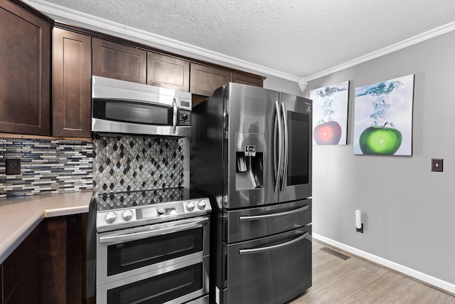 kitchen with appliances with stainless steel finishes, ornamental molding, dark brown cabinets, and decorative backsplash