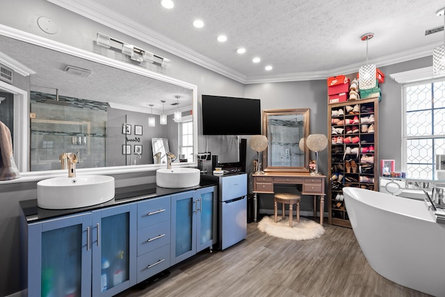 bathroom with ornamental molding, shower with separate bathtub, wood-type flooring, a textured ceiling, and vanity