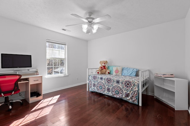 bedroom featuring ceiling fan, dark hardwood / wood-style floors, and a textured ceiling