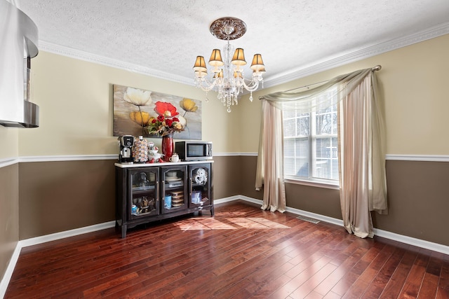 unfurnished dining area featuring a chandelier, dark hardwood / wood-style floors, a textured ceiling, and crown molding