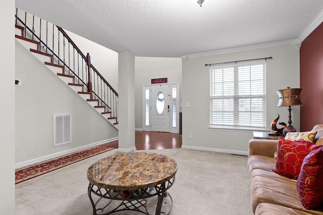 carpeted entrance foyer featuring a textured ceiling and ornamental molding