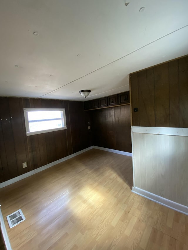 spare room featuring wooden walls and light hardwood / wood-style floors