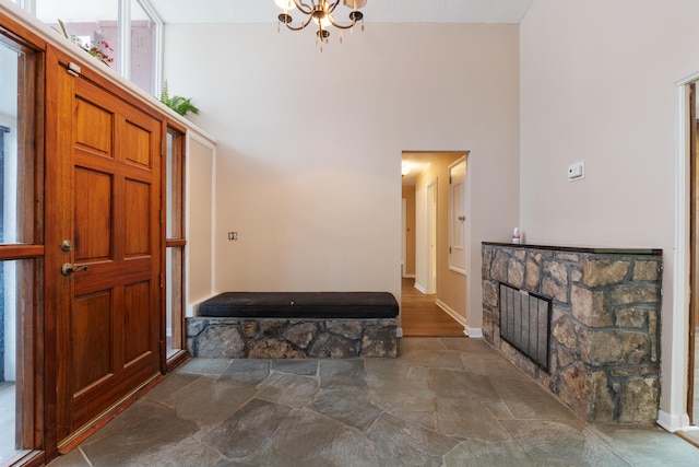 entryway with a fireplace, stone finish floor, a towering ceiling, and baseboards