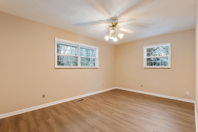 unfurnished room with wood finished floors, visible vents, a ceiling fan, baseboards, and a textured ceiling