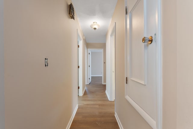 corridor with baseboards and light wood finished floors