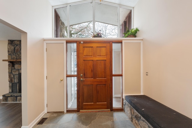 entrance foyer featuring baseboards, visible vents, and a stone fireplace