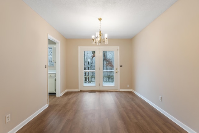 unfurnished dining area with baseboards, dark wood-style floors, a textured ceiling, and a notable chandelier