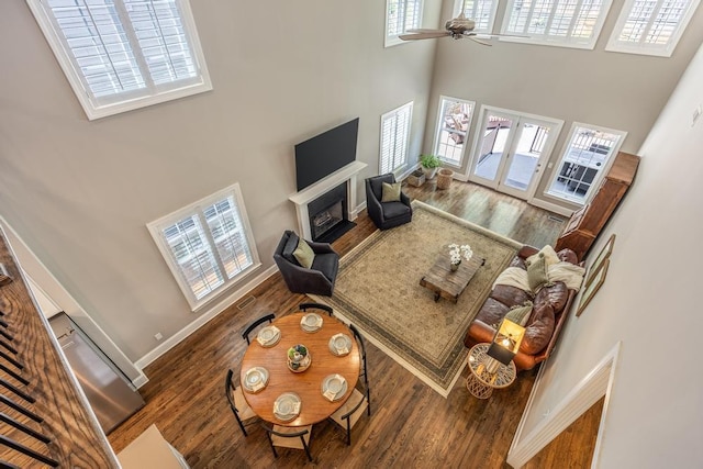 living room featuring french doors, ceiling fan, wood-type flooring, and a high ceiling