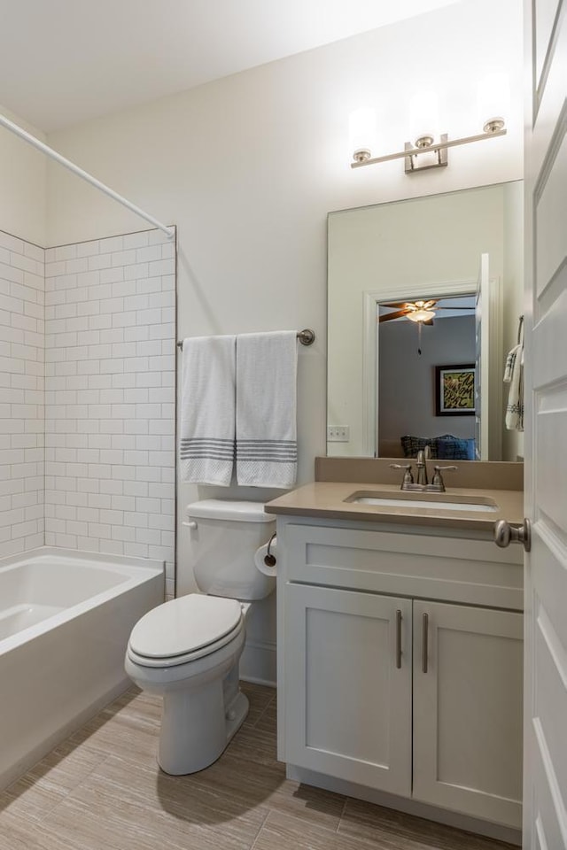 full bathroom with ceiling fan, tiled shower / bath, vanity, and toilet