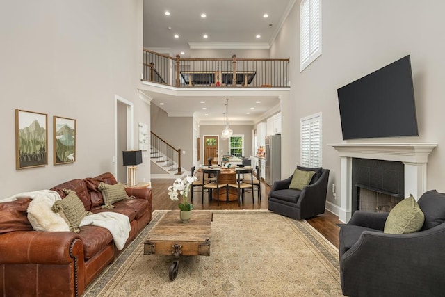 living room with a high ceiling, wood-type flooring, ornamental molding, and a fireplace