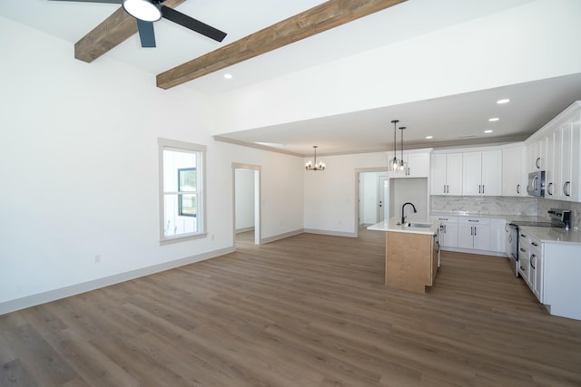 kitchen featuring a kitchen island with sink, stainless steel appliances, white cabinets, decorative backsplash, and beamed ceiling