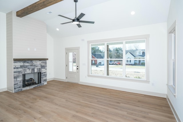 unfurnished living room featuring ceiling fan, a fireplace, lofted ceiling with beams, and light hardwood / wood-style flooring