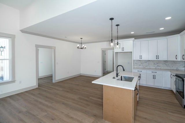 kitchen featuring hanging light fixtures, sink, a center island with sink, and white cabinets