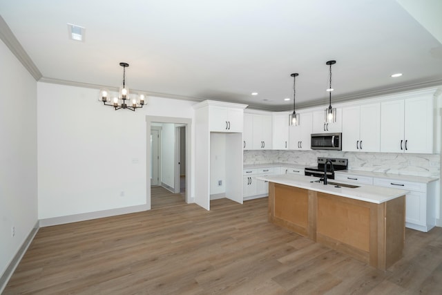 kitchen featuring decorative light fixtures, sink, white cabinets, a kitchen island with sink, and stainless steel appliances