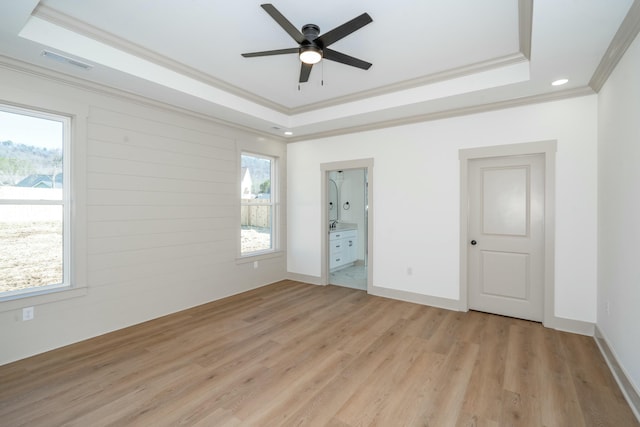 unfurnished bedroom with a raised ceiling and multiple windows