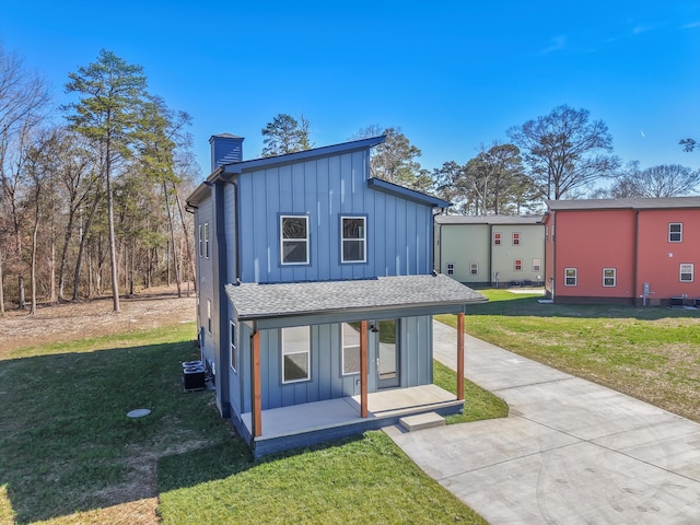 view of front of property featuring board and batten siding, a chimney, and a front lawn