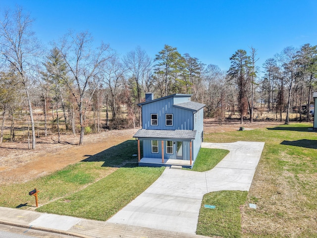 view of front facade with board and batten siding, concrete driveway, a chimney, and a front lawn