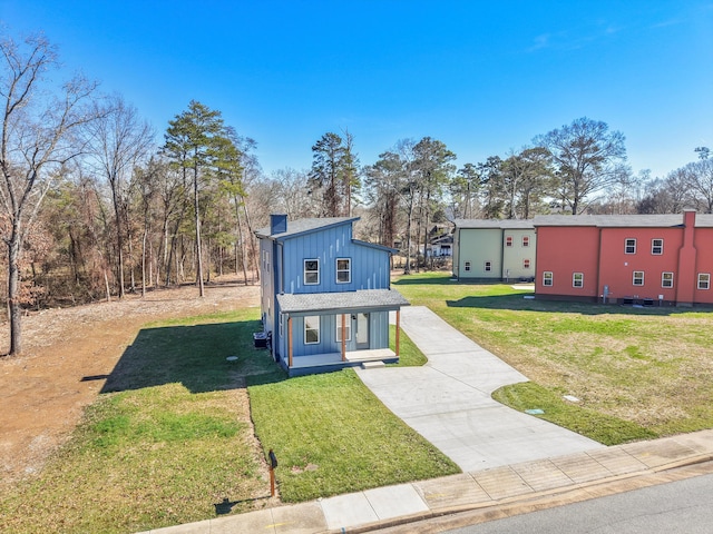 view of front of home featuring board and batten siding, covered porch, a chimney, and a front lawn