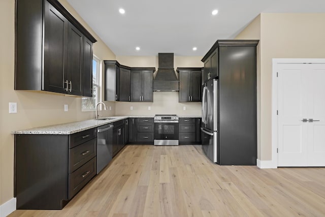 kitchen featuring light stone counters, stainless steel appliances, premium range hood, a sink, and light wood-style floors