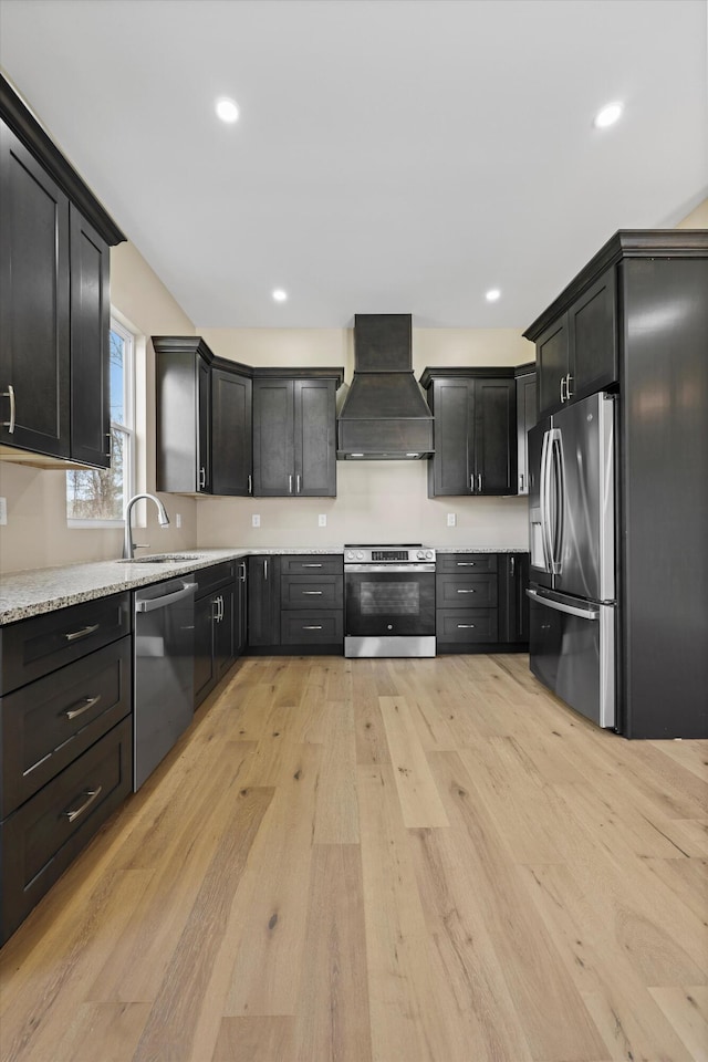 kitchen featuring light stone counters, a sink, light wood-style floors, appliances with stainless steel finishes, and custom range hood