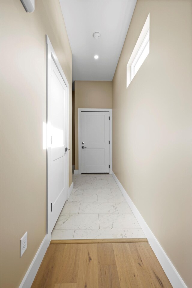 hall featuring marble finish floor and baseboards