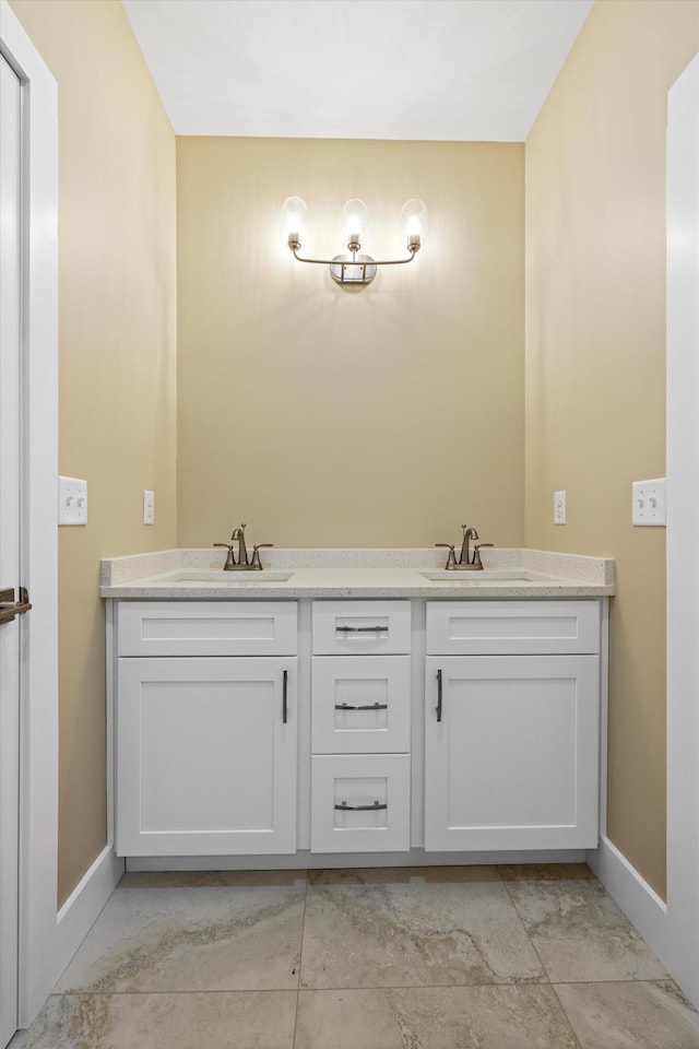 full bathroom featuring double vanity, baseboards, and a sink