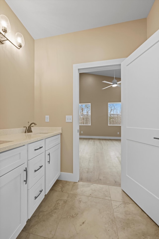 bathroom featuring double vanity, a sink, a ceiling fan, and baseboards