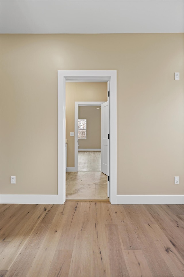 unfurnished room with light wood-style flooring and baseboards