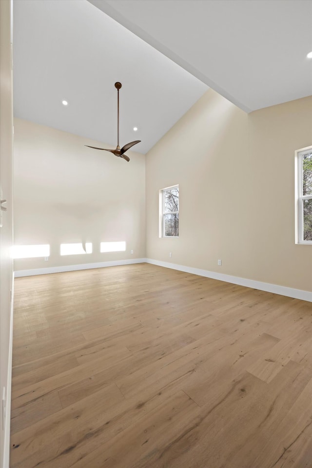 spare room with light wood-type flooring, ceiling fan, baseboards, and vaulted ceiling