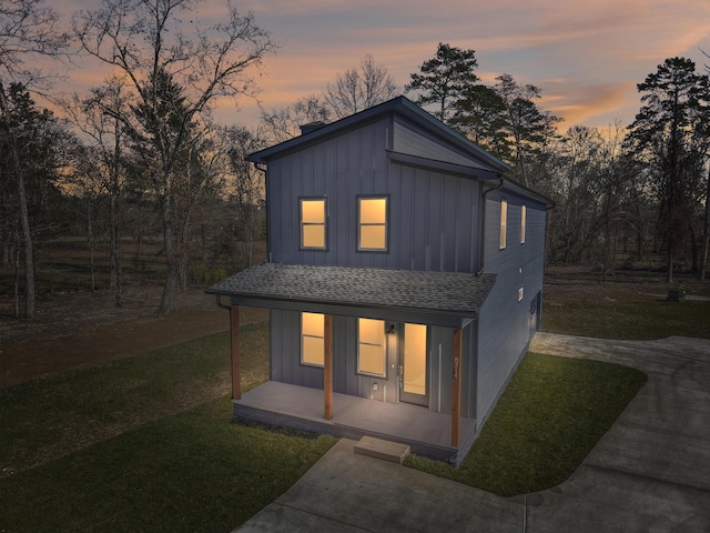 view of front of house featuring a shingled roof, board and batten siding, and a front yard