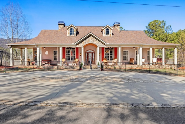 view of front of property featuring covered porch, a fenced front yard, a chimney, and a ceiling fan