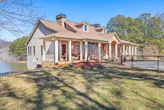 view of front of home with a water view, a porch, fence, and a front lawn