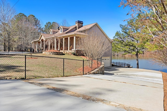 view of property exterior featuring concrete driveway, a water view, a yard, and fence