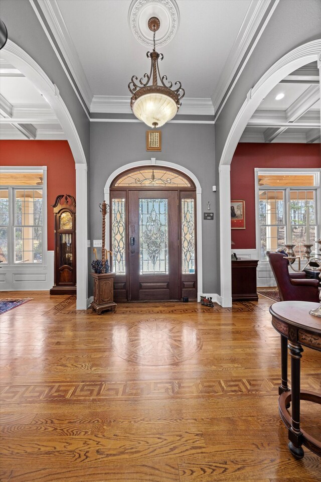 entryway with coffered ceiling, arched walkways, a healthy amount of sunlight, and wood finished floors