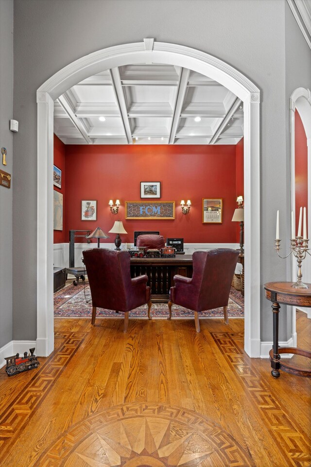 dining room with arched walkways, baseboards, coffered ceiling, wood finished floors, and beamed ceiling