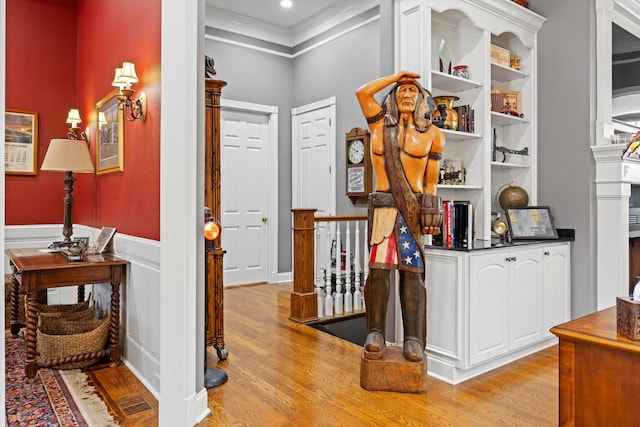 hallway with light wood finished floors, recessed lighting, crown molding, and wainscoting