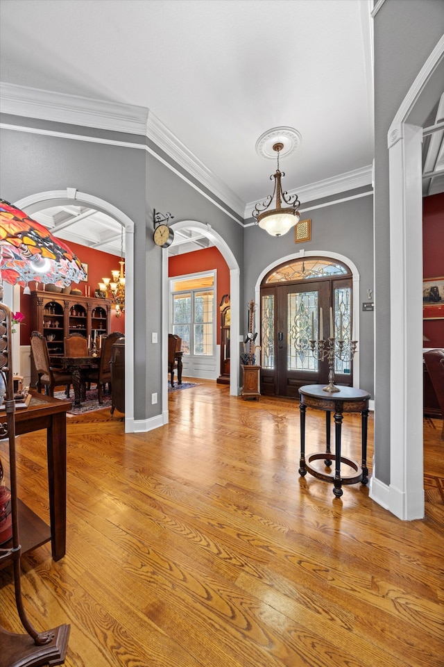 entryway with arched walkways, crown molding, light wood-type flooring, and baseboards